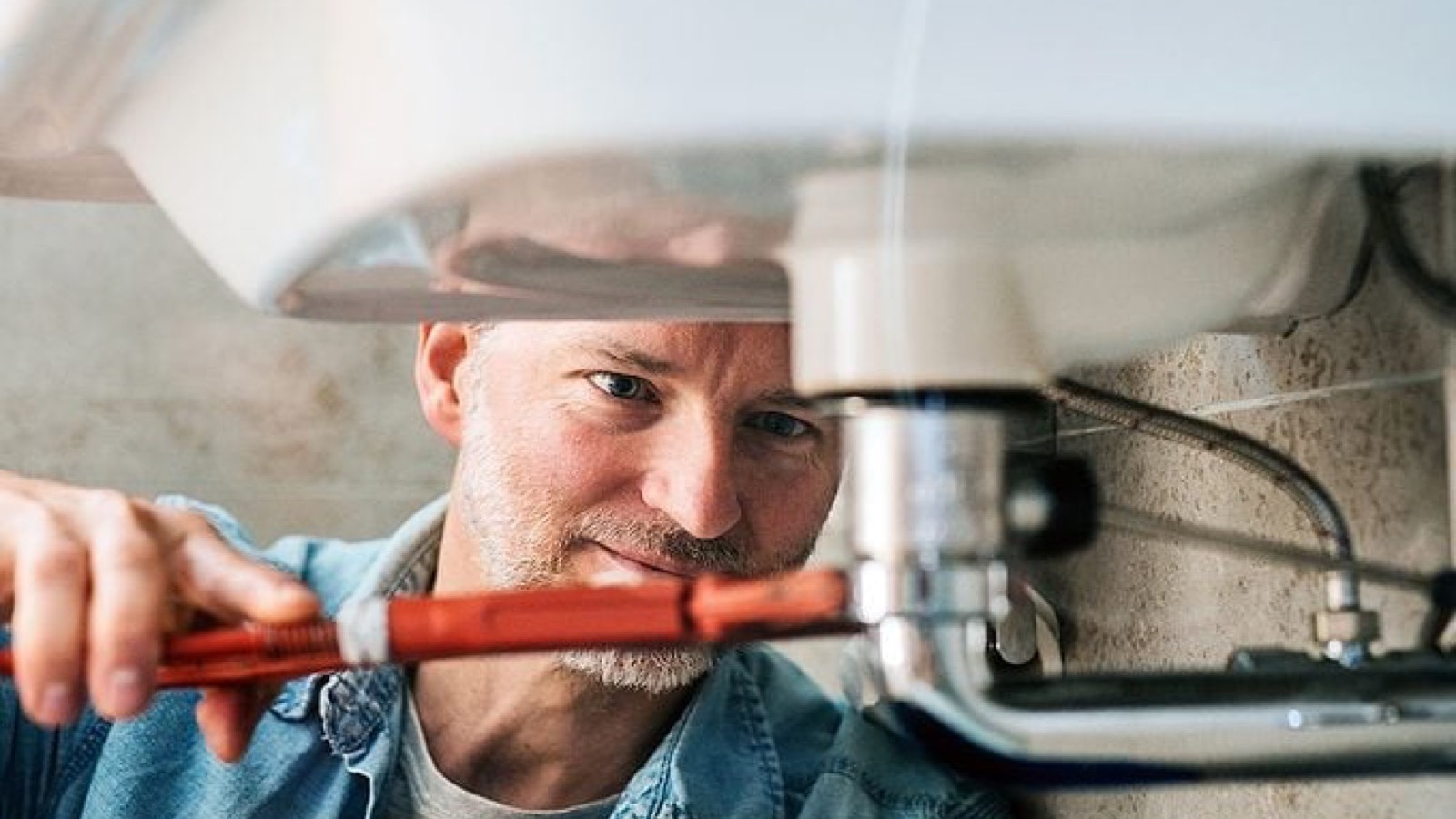 Plumbing professional inspecting a connection inside a Gilbert home